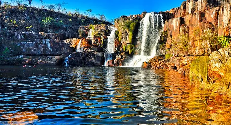 Paredão rochoso, com duas quedas d'água que desaguam em um lago na Chapada dos Veadeiros em lugares para viajar no brasil